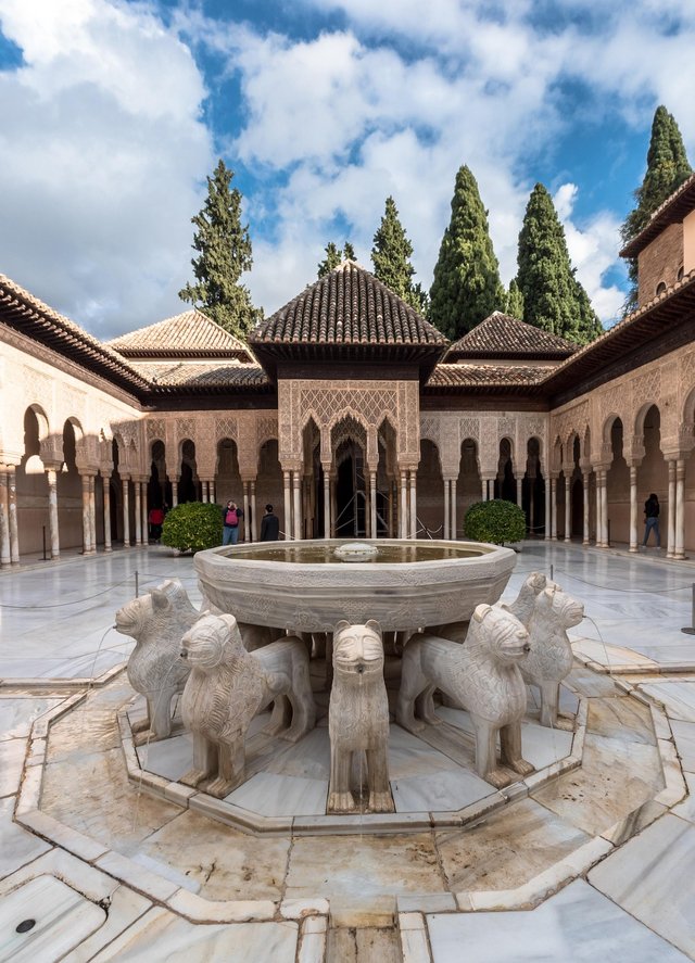 Löwenhof der Alhambra mit zentralem Marmorbassin auf zwölf steinernen Löwen, umgeben von filigranen Arkaden. Der Hof wurde im 14. Jahrhundert unter Muhammad V. erbaut und ist eines der bekanntesten Beispiele nasridischer Palastarchitektur.